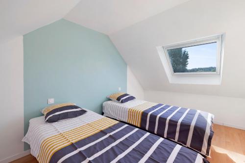 two beds in a room with a window at Gite cap 3KM plages in Telgruc-sur-Mer