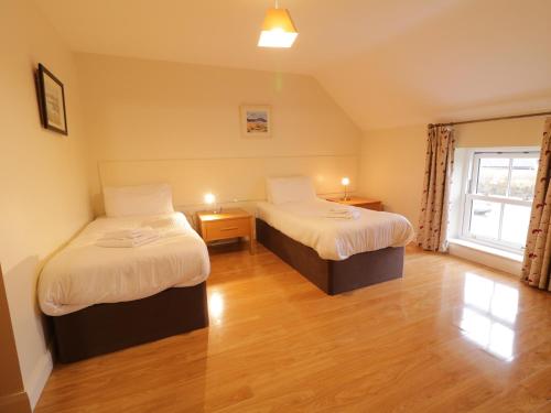 a hotel room with two beds and a window at Foyle Cottage in Strabane