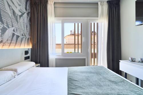 a hotel room with a bed and a window at Hostal Sol y Miel in Benalmádena