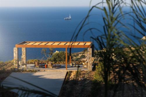 a pavilion with a view of the ocean with a boat at Elysium Caved Villas - Carved From Calm by etouri in Heraklio