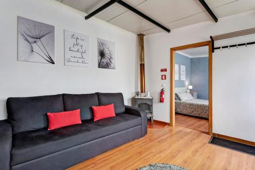 a living room with a black couch and a bedroom at Casinha do coração do Oeste in Cadaval