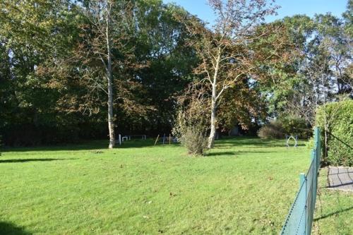 a fence in a field with trees in the background at Ferienappartment Lhasa Apso in Dornum