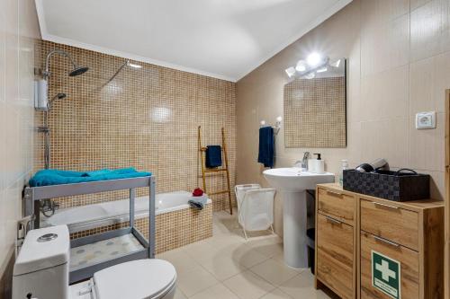 a bathroom with a toilet and a sink and a tub at Casinha do coração do Oeste in Cadaval