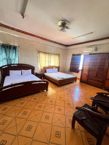a bedroom with two beds and a table and a couch at Khách Sạn Vũ Nam Hưng in Ấp Hưng Lộc