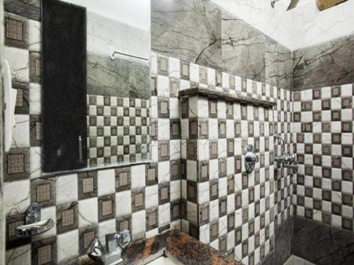 a bathroom with a tiled shower with a sink at Hotel Grand in Dehradun