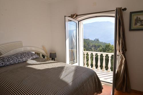 a bedroom with a bed and a door to a balcony at Casa Estrela de Alva in Seia
