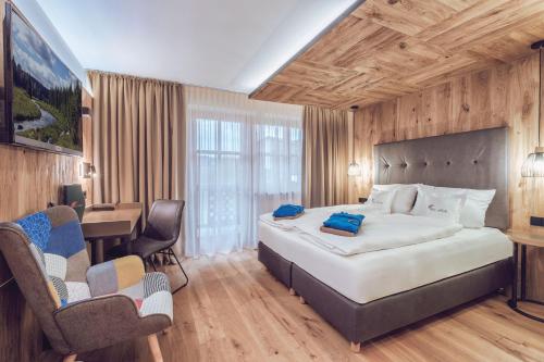 a bedroom with a large bed with a desk and chairs at Hotel MY Kramerwirt in Geiersthal