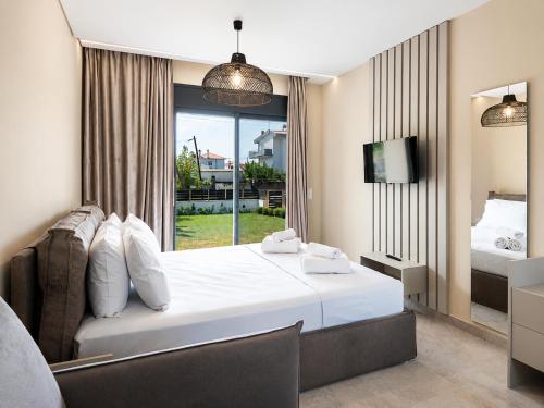 a bedroom with a large white bed and a window at Mulberry Suites in Paralia Dionysiou