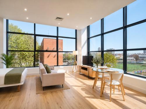 a bedroom with large windows and a bed and a table at Paseo Suites Hotel in Madrid