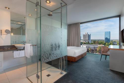 a bathroom with a shower and a sink and a bed at Windmill Frankfurt Niederrad in Frankfurt