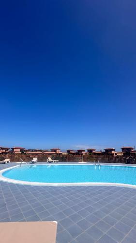 a large swimming pool with chairs and the ocean in the background at Fuerte Wave House in Lajares