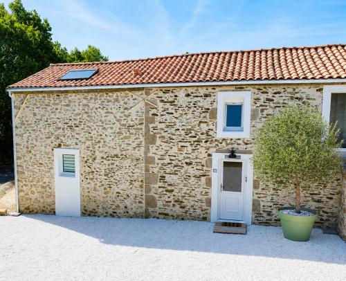 a stone building with a white door and a tree at Villa Bella & Spa in Mouilleron-le-Captif