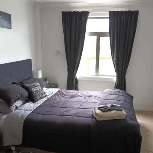 a bedroom with a bed with black curtains and a window at Ahaura Hotel in Greymouth