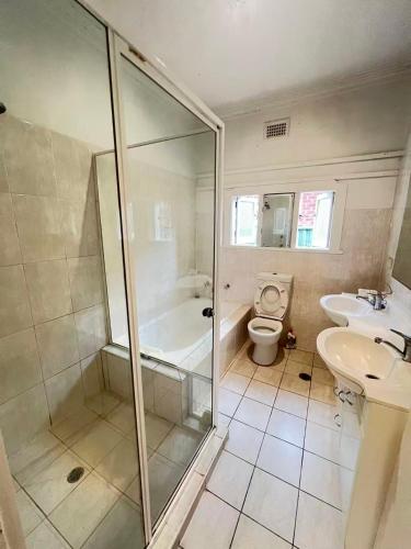 a bathroom with a shower and a toilet and a sink at Room 73 in Merrylands