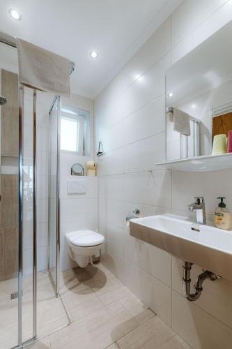 a white bathroom with a toilet and a sink at Haus Lackner am Weissensee in Kärnten in Weissensee