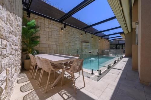 a patio with a table and chairs and a swimming pool at Villa Lausanne - View in Dāliyat el Karmil