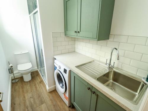 a kitchen with a sink and a washing machine at Bobblehat Barn in Alford
