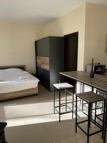 a bedroom with a bed and a table and two stools at Chalet 102 - Zresidence - Faitroun in Al ‘Aqabah