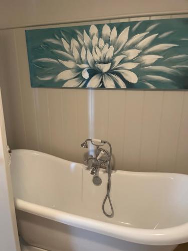 a bathroom sink with a flower painting on the wall at Gorse cottage in Newton Abbot