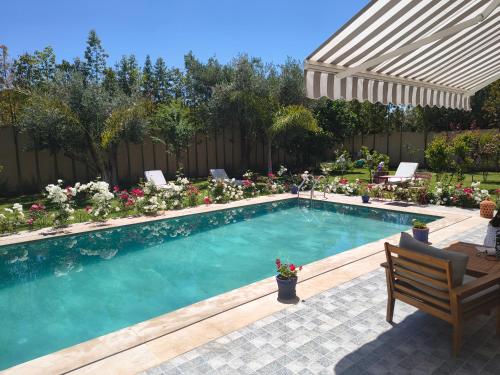 a swimming pool with a bench and an umbrella at Dar Zaytouna in Oulad Akkou