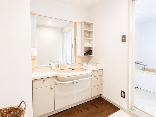 a white bathroom with a sink and a mirror at The Little Kamakura Hotel 鎌倉駅徒歩2分 in Kamakura