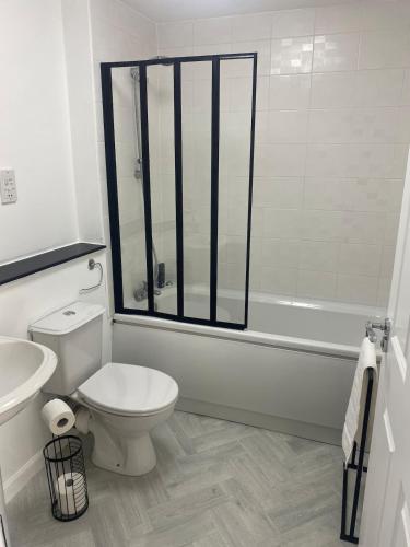 a bathroom with a toilet and a tub and a sink at Harbour Point Apartment in Saltcoats