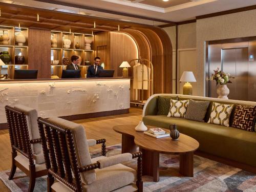 a lobby with a couch and two people in a salon at Grand Hôtel Roi René Aix - MGallery Collection in Aix-en-Provence