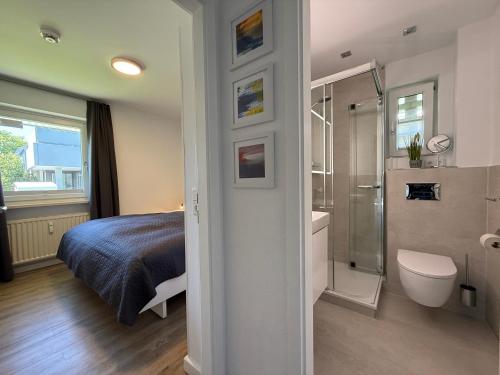 a bedroom with a bed and a bathroom with a shower at Käpt'n Gordon, App 2 in Wenningstedt