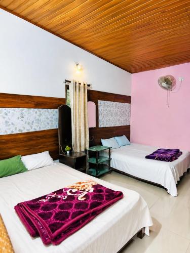 a room with two beds with purple blankets on them at munnar Green portico Cottages in Anachal