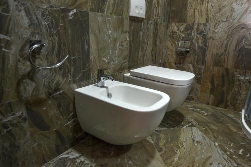 a bathroom with a white toilet and a sink at Hotel Pandora Residence in Tirana