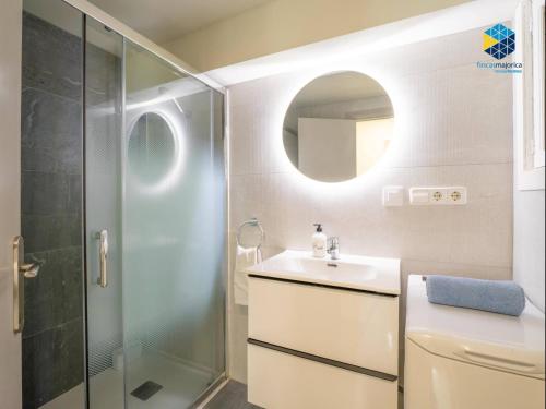 a bathroom with a shower and a sink and a mirror at Apartamento Rocamar in S'Illot