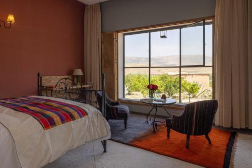 a bedroom with a bed and a table and a large window at Kasbah Beldi in Lalla Takerkoust