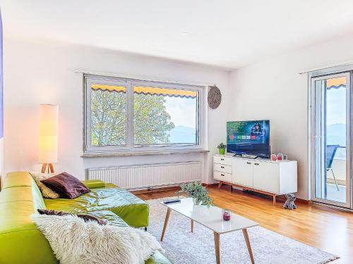 a living room with a green couch and a tv at Apartment Apt-Woka by Interhome in Aldesago