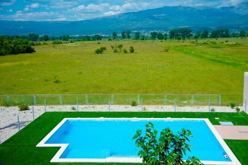a swimming pool in a field next to a field at Vacation apartments Mario with salt water pool in Turjaci