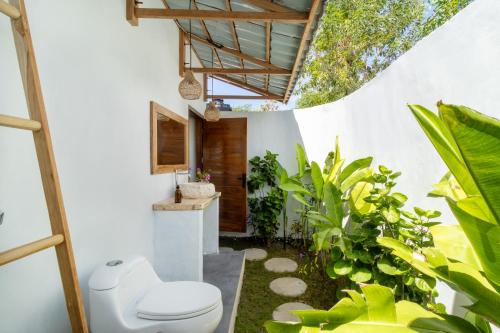 a bathroom with a toilet and some plants at Breath House Penida in Polilit