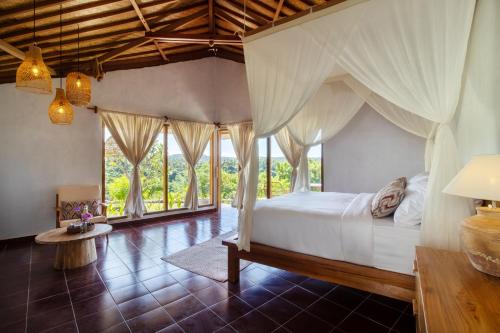 a bedroom with a canopy bed with windows at Breath House Penida in Polilit