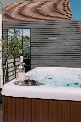 a hot tub with a bottle of wine and glasses at The Hamptons Beach House in East Preston