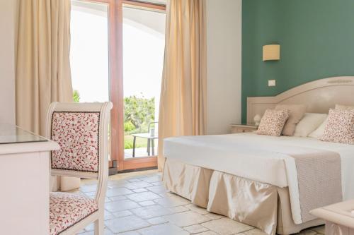 a bedroom with a white bed and a balcony at B&B La Vigna in Carovigno