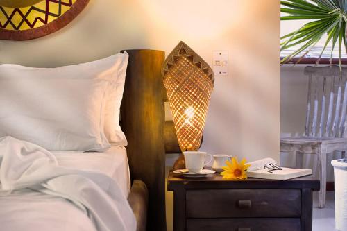 a bedroom with a bed and a nightstand with a table with a lamp at Eco Resort Vento Leste in Jericoacoara