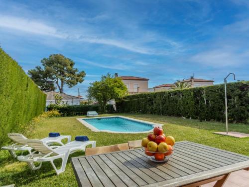 a bowl of fruit on a table next to a pool at Villa Calas III by Interhome in L'Ametlla de Mar