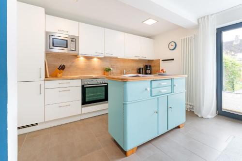 a kitchen with white cabinets and a blue island at Fischerhus Laboe in Laboe