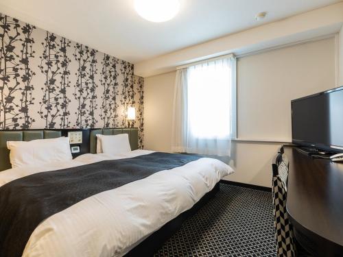 a hotel room with a bed and a flat screen tv at APA Hotel Sapporo Susukino Ekimae in Sapporo