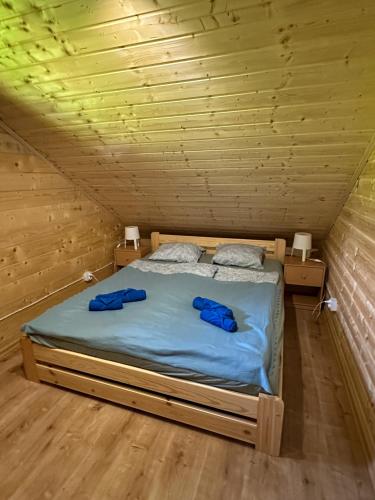 a bed in a wooden room with two blue robes on it at Chatki Bies-Czadowe-Bies in Berezka