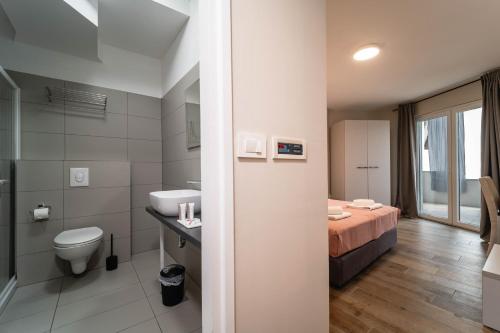 a bathroom with a bed and a sink and a toilet at Hotel Plaza in Pag
