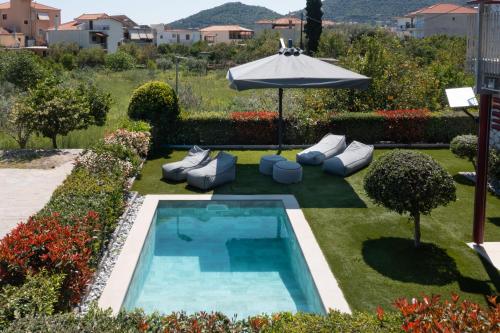 a backyard with a swimming pool and an umbrella at Tyros Boutique Houses Villas in Tyros