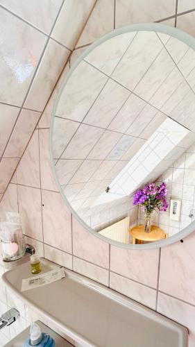 ein Badezimmer mit einem Spiegel über der Badewanne in der Unterkunft Staytopus Pension - Heidepark, Kartbahn, Sauna ink, Garden, BBQ in Schneverdingen