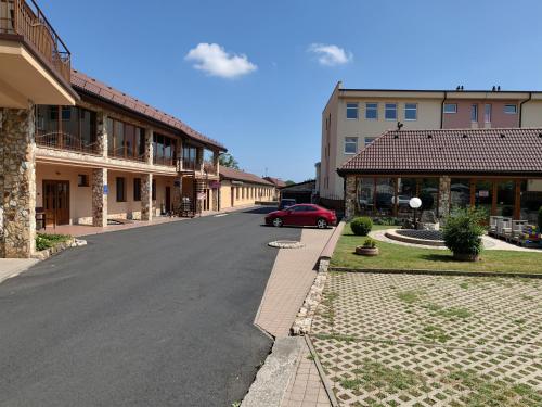 a street in a town with buildings and a red car at Areál SLZA in Sečovce