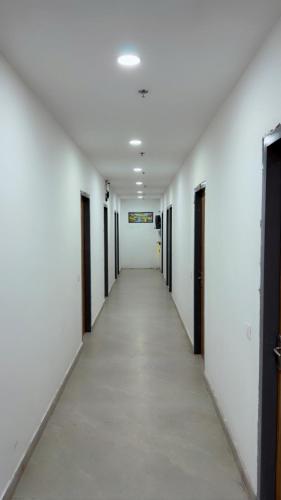 an empty hallway with white walls and a long corridor at Hotel Aura Avenue in Bathinda