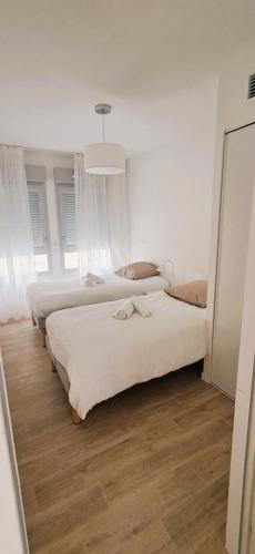 two beds in a room with white walls and wood floors at Résidence de Bergerac in Bergerac