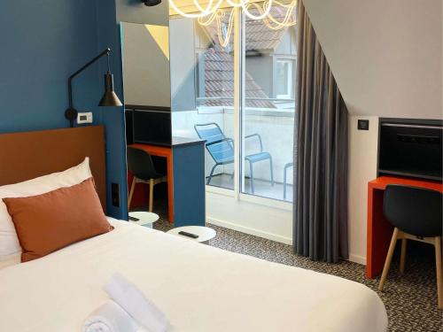 a hotel room with a bed and a desk and chairs at ibis Colmar Centre in Colmar